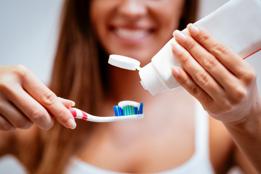 young woman putting toothpaste on toothbrush 